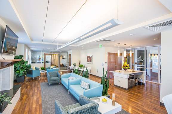 A modern office space with a blue couch and a television on the wall.