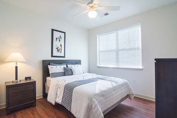 A bedroom with a bed, nightstand, and a picture on the wall.