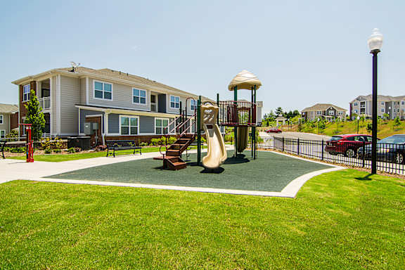 A playground with a slide and a swing set in front of a building.