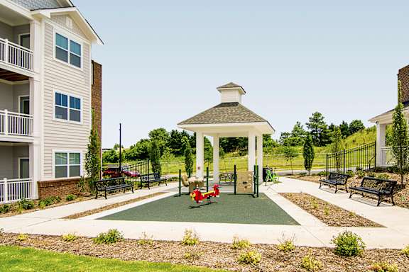 A gazebo is surrounded by benches in a park-like setting.