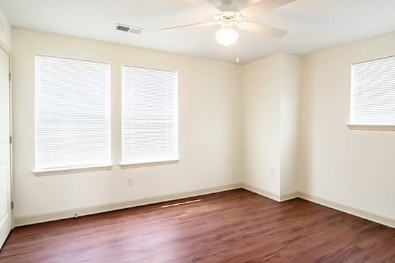 A room with a ceiling fan and two windows.
