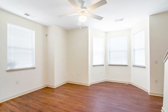 A room with a ceiling fan and wooden flooring.