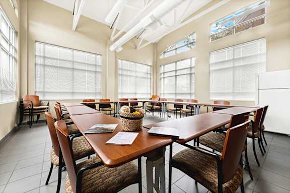 a meeting room with tables and chairs and large windows