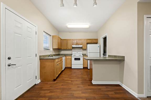 an empty kitchen with wood flooring and white appliances