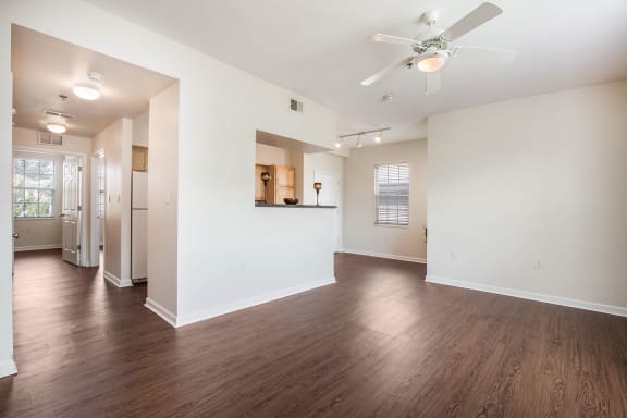 an empty living room with a ceiling fan and hard wood floors