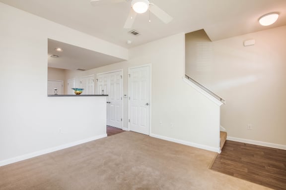 a living room and kitchen with white walls and a ceiling fan