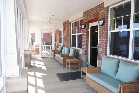 a porch with furniture and a brick wall at University Place Senior