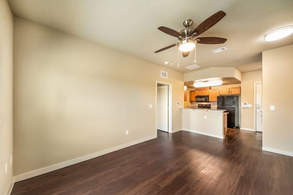 an empty living room with a ceiling fan and a kitchenat Wheatley Park Senior Living San Antonio