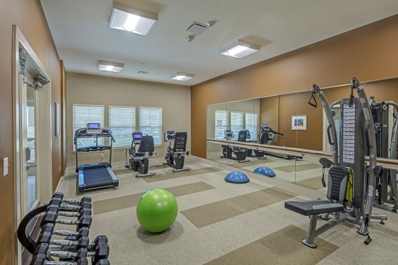 a gym with cardio machines and weights and mirrors at Wheatley Senior Living San Antonio
