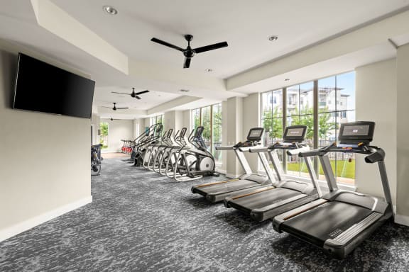 a gym with cardio machines and a tv