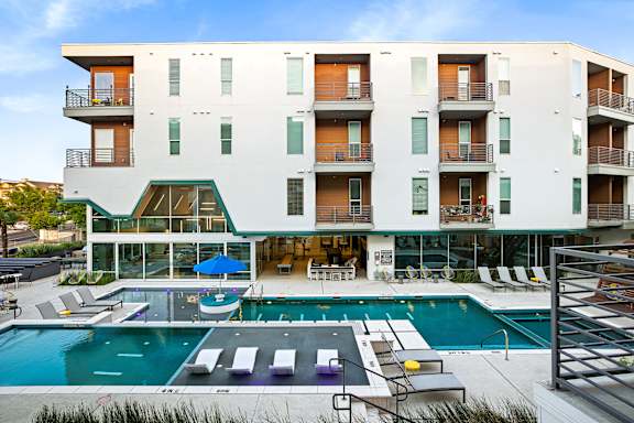 A modern apartment building with a pool in front.