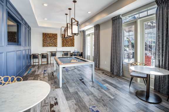 A room with a pool table and a dining table.