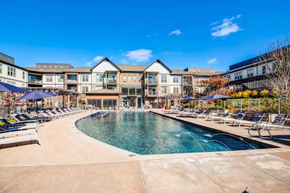 A large outdoor swimming pool surrounded by lounge chairs and umbrellas.
