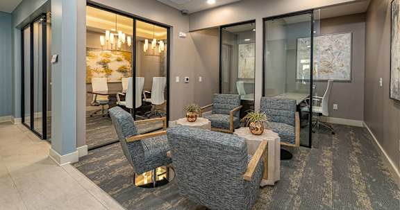 A modern living room with a glass table and grey chairs.