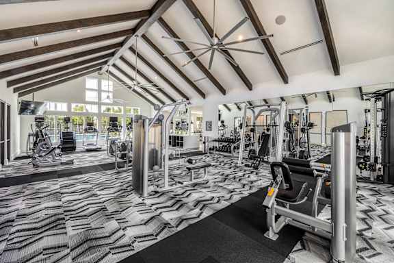 A gym with a variety of equipment including treadmills, weights, and exercise machines.