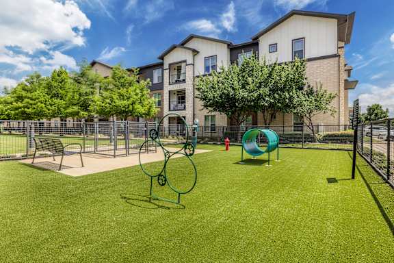 A playground with a slide, swings, and a bench in front of a building.