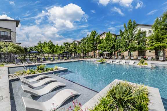 A pool surrounded by trees and a building in the background.