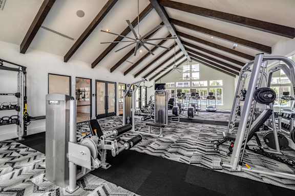 A gym with a variety of equipment including a treadmill, weights, and a bench press.