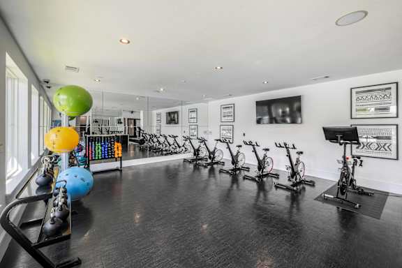A gym with exercise equipment and a wall of pictures.