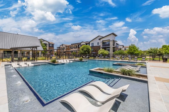 a swimming pool with lounge chairs and buildings in the background
