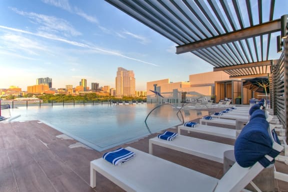 a pool with lounge chairs and a view of the city