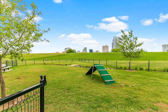 A playground with a green slide and a black fence.