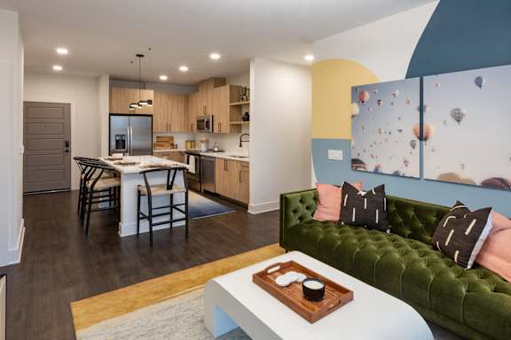 A modern kitchen with a dining table and a green couch.