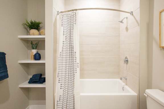 A white bathroom with a white tub and a white shower curtain.