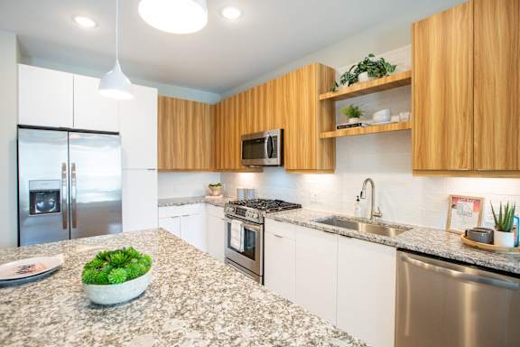 A modern kitchen with wooden cabinets and granite countertops.