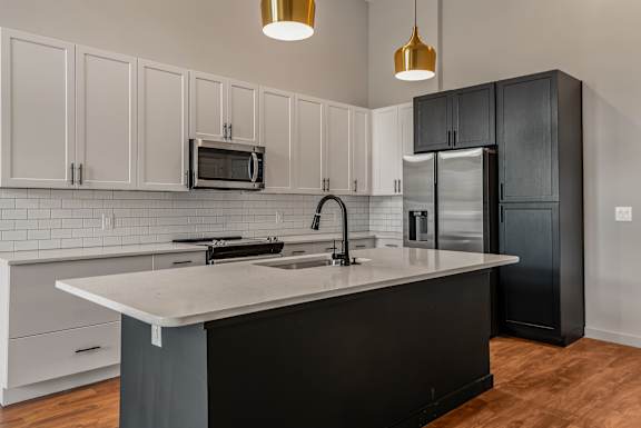 A kitchen with a black island and white cabinets.