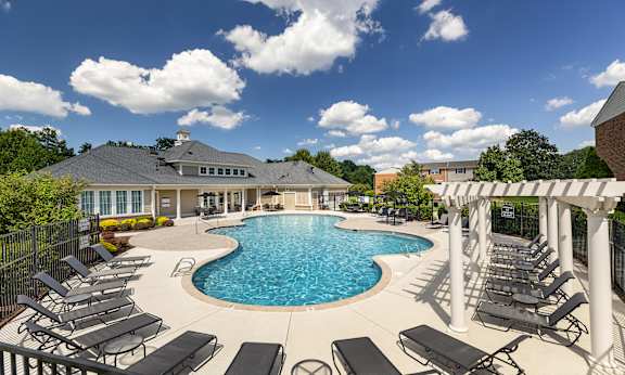 A large outdoor swimming pool surrounded by sun loungers and a covered seating area.