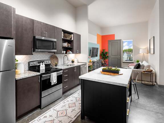 A kitchen with a refrigerator, microwave, oven, and sink.