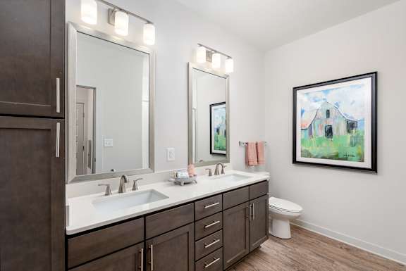 A bathroom with a white sink and brown cabinets.