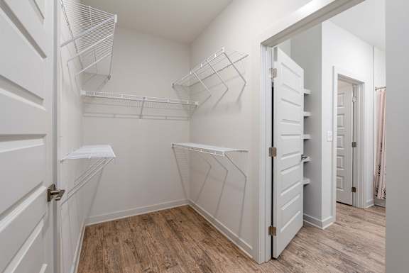 A white closet with shelves and a wooden floor.