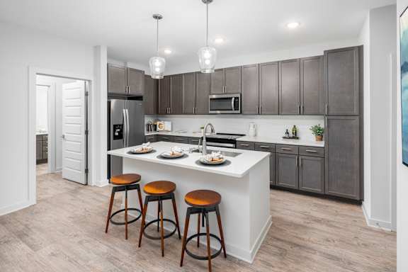 A kitchen with a white island and brown bar stools.