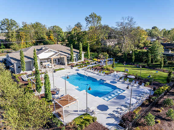 A large outdoor swimming pool surrounded by trees and a building.