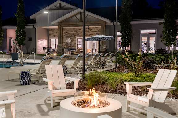A fire pit sits in the middle of a patio surrounded by chairs.