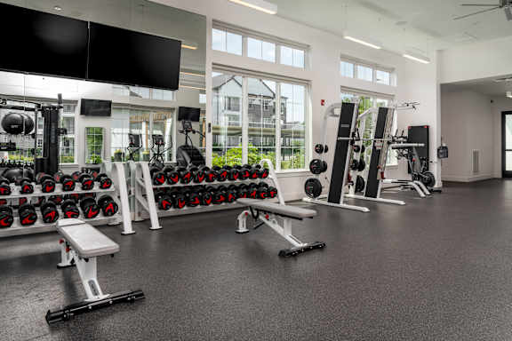 A gym with a variety of equipment including dumbbells, weight machines, and benches.