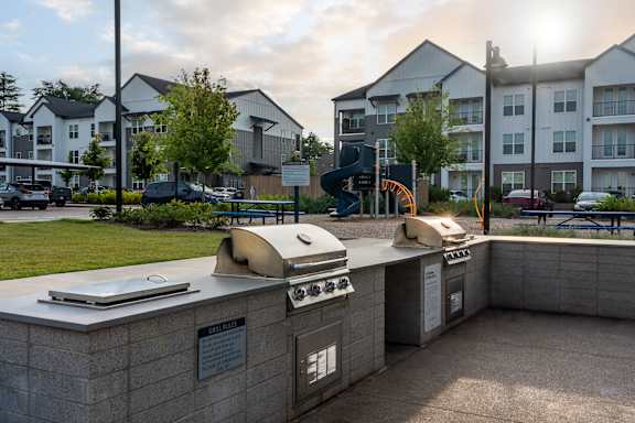 A sunny day at a residential complex with a bbq grill in the foreground.
