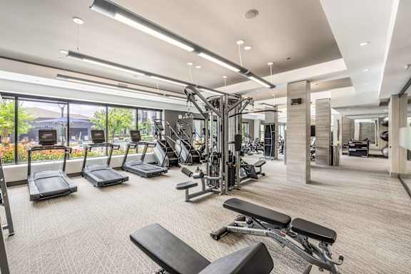 A spacious gym with a variety of equipment and a view of the outdoors.