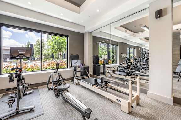 A spacious gym with treadmills, exercise bikes, and a television.