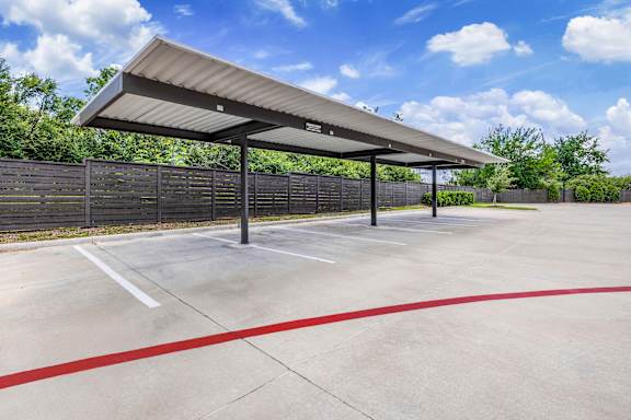 A parking lot with a canopy and red lines on the ground.