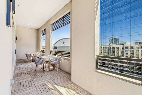 A balcony with a table and chairs overlooks a cityscape.