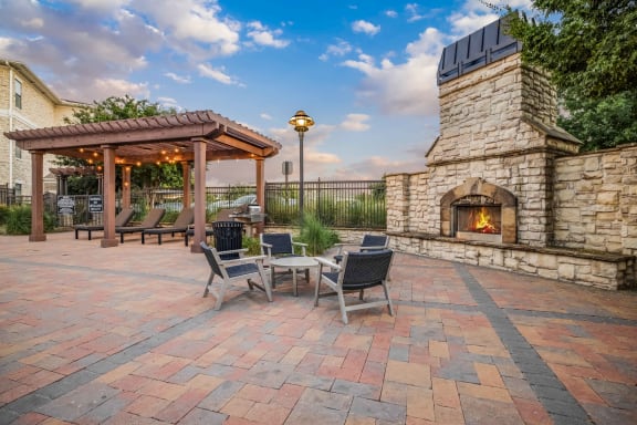 a patio with a stone fireplace and a table with chairs