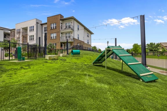 a backyard with a swing set and a seesaw in front of an apartment building