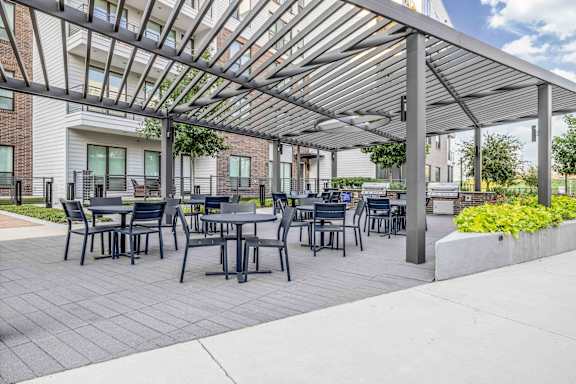 A patio with tables and chairs under a metal roof.