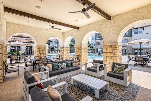 A patio with a pool and a table with chairs.