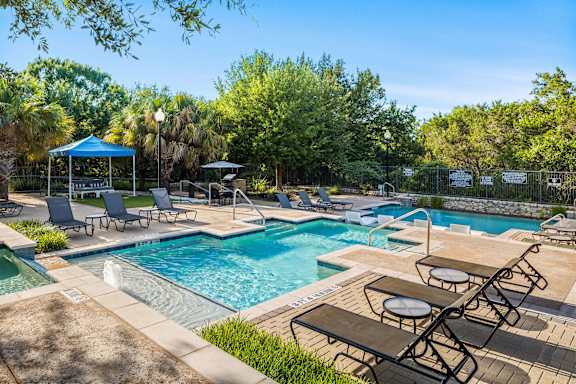 A pool area with sun loungers and a gazebo.
