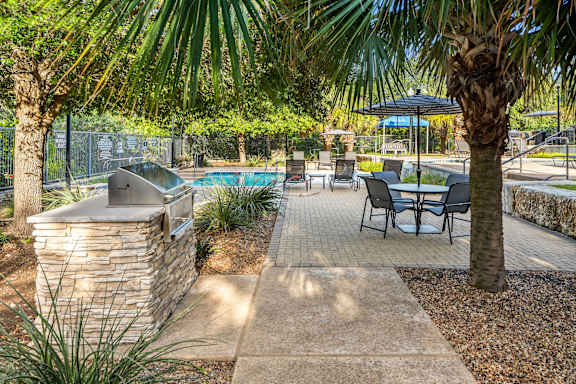 A patio area with a table and chairs and a pool in the background.