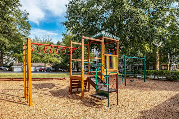 A playground with a swing set, a slide, and a wooden structure.